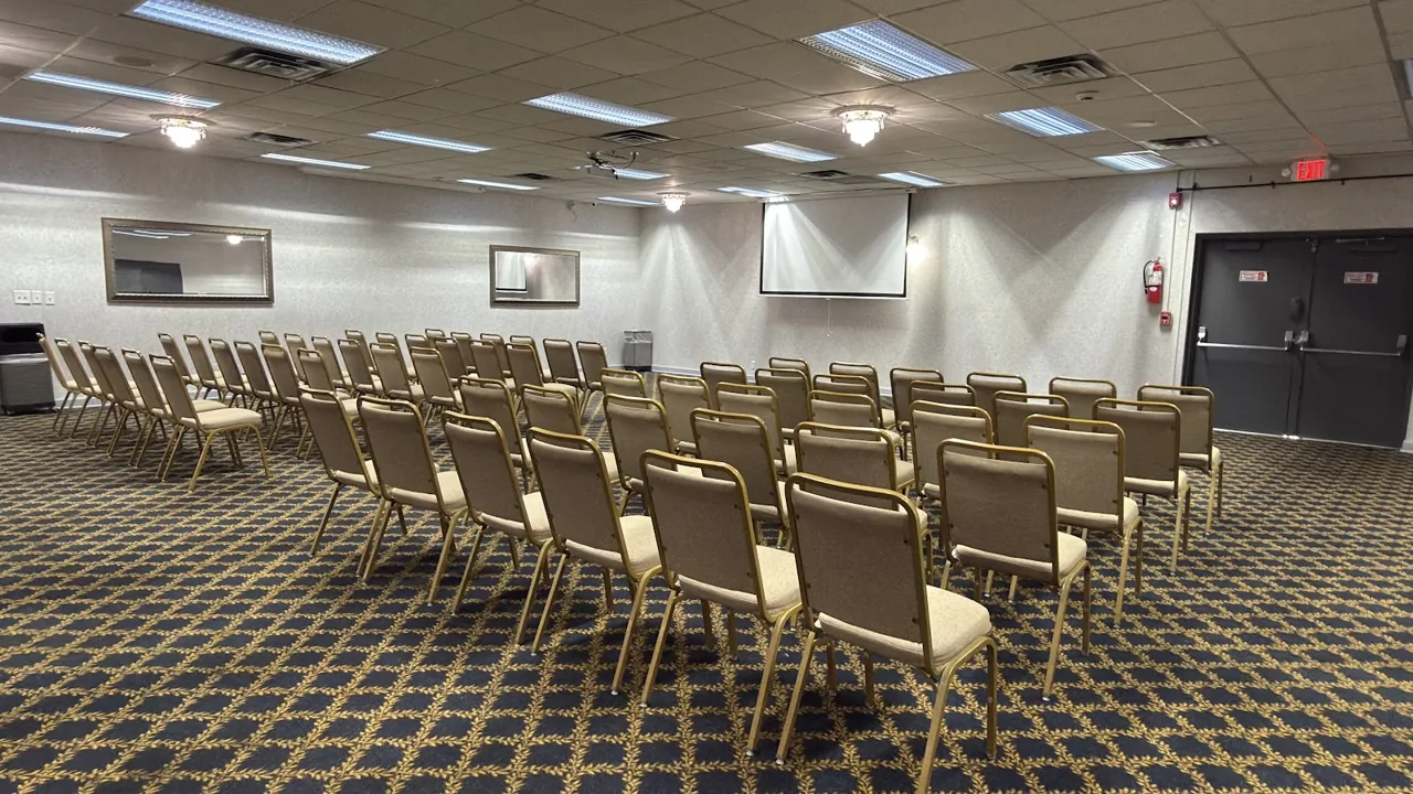 Banquet hall decorated for a wedding reception with gold centerpieces and draped chairs